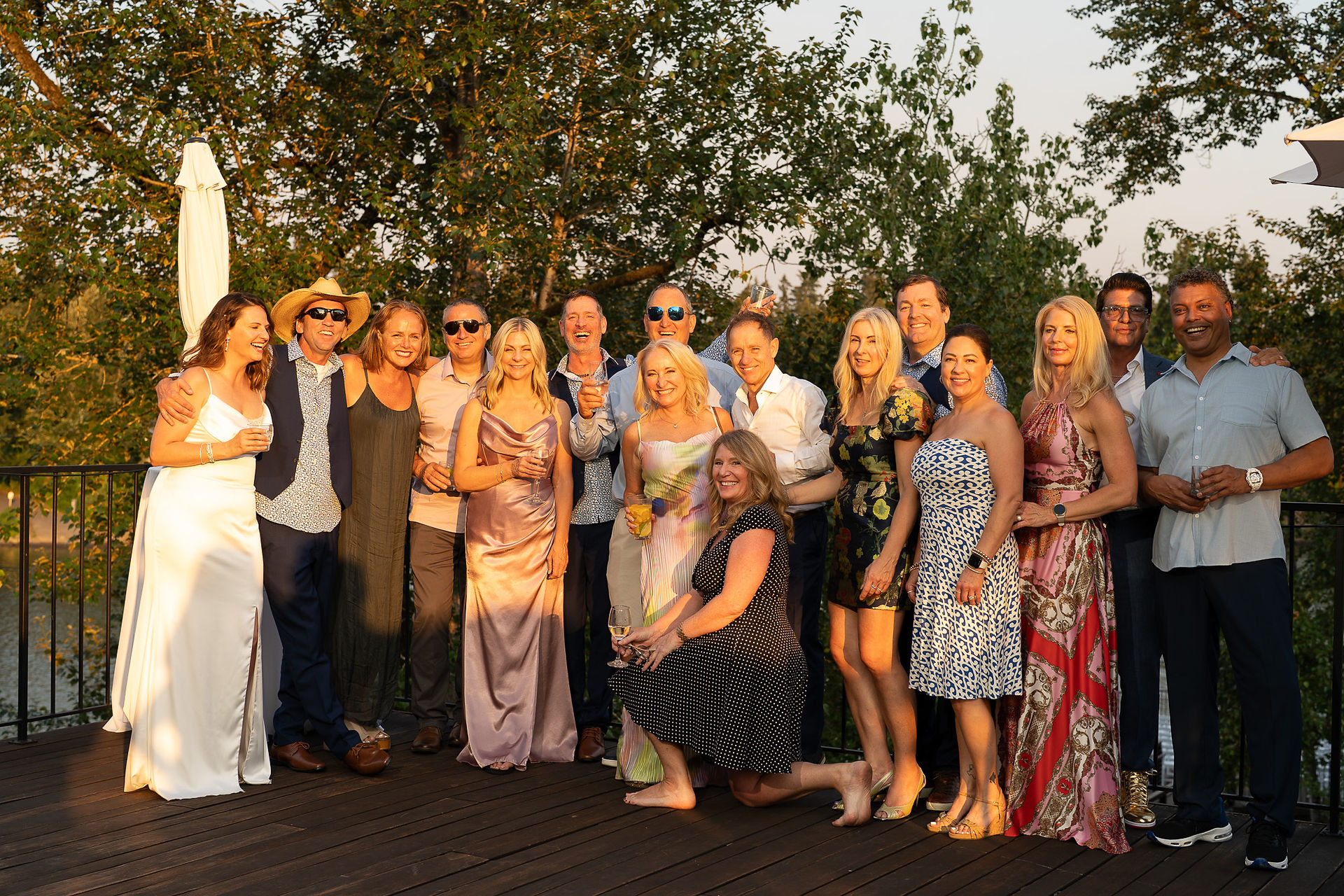 Large group of smiling adults posing outdoors at a summer celebration.
