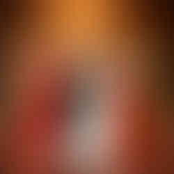 Bride and three women in colorful gowns holding flowers, elegant setting.