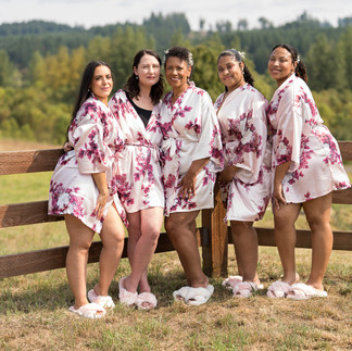 Five women in matching floral robes and slippers outdoors.