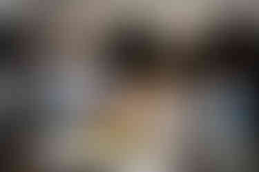 Wedding guests listen as man speaks into microphone at outdoor reception.