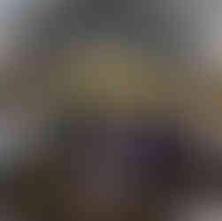 Couple seated at wedding reception under tent with guests and hills.