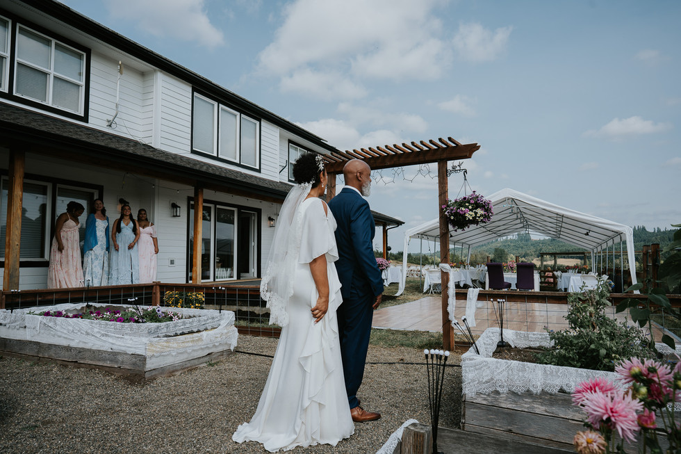 Bride and father walking to outdoor farm wedding ceremony.