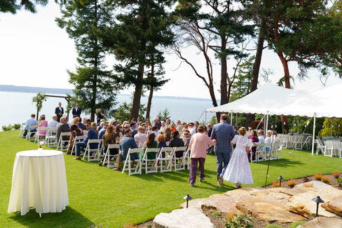 Guests seated at outdoor wedding ceremony on a beautiful grassy lawn.