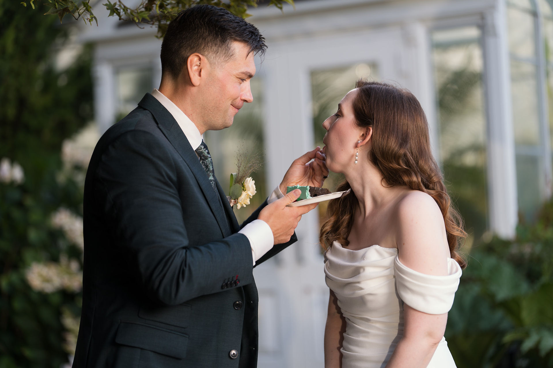 Groom feeding cake to bride at Volunteer Park Conservatory in Seattle