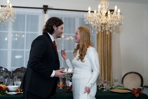Bride feeds groom cake at their wedding reception, smiling.