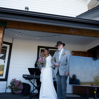 Bride and father walk down aisle at an outdoor farm wedding.