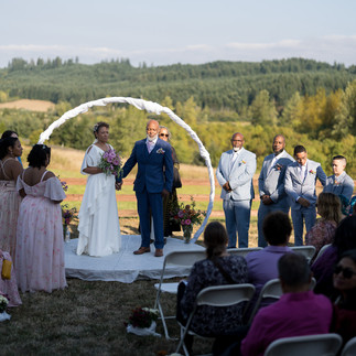 Bride and groom holding hands during intimate farm wedding ceremony outdoors.