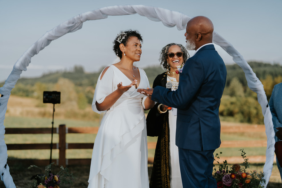Bride and groom exchanging rings during an outdoor farm wedding ceremony.