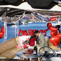 Romantic boat proposal: "Marry Me" banner, roses, happy couple