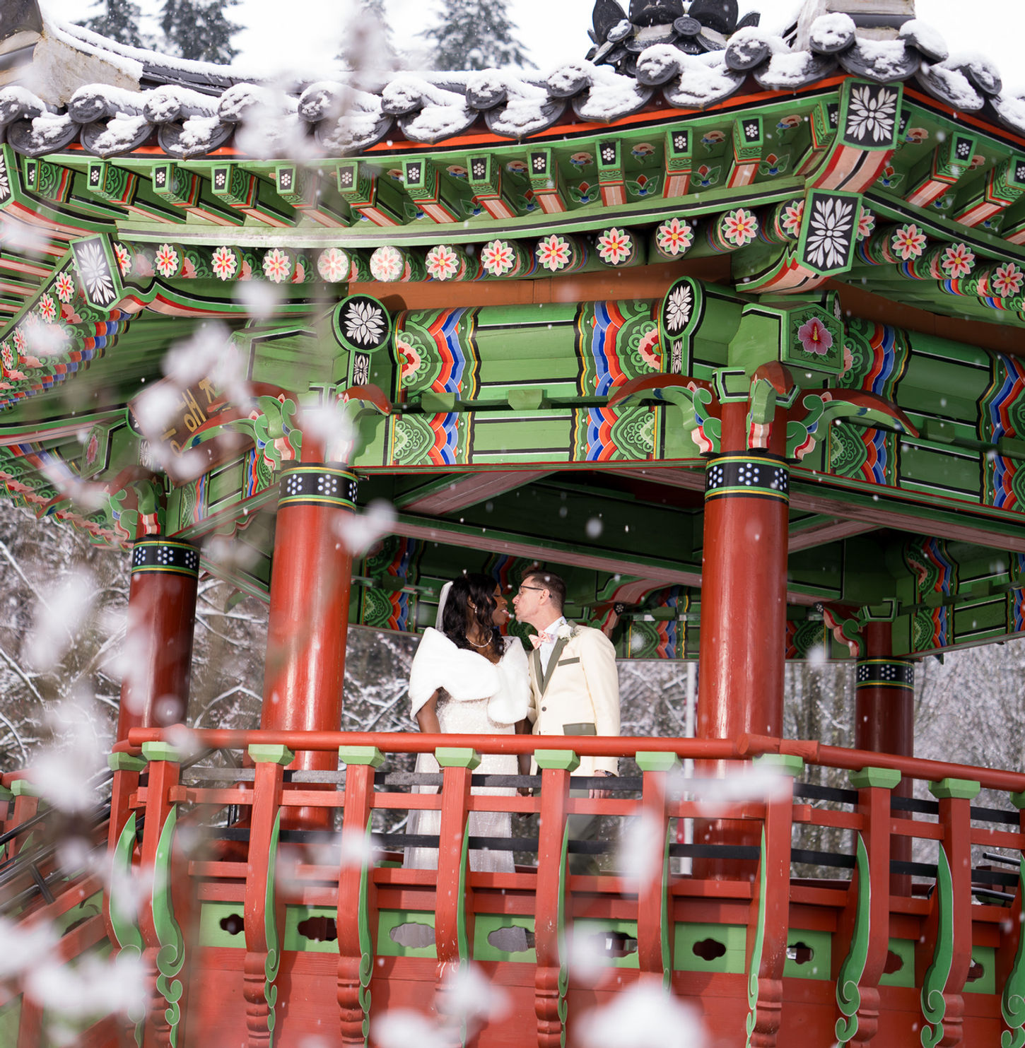 Wedding couple kissing in a snowy traditional gazebo