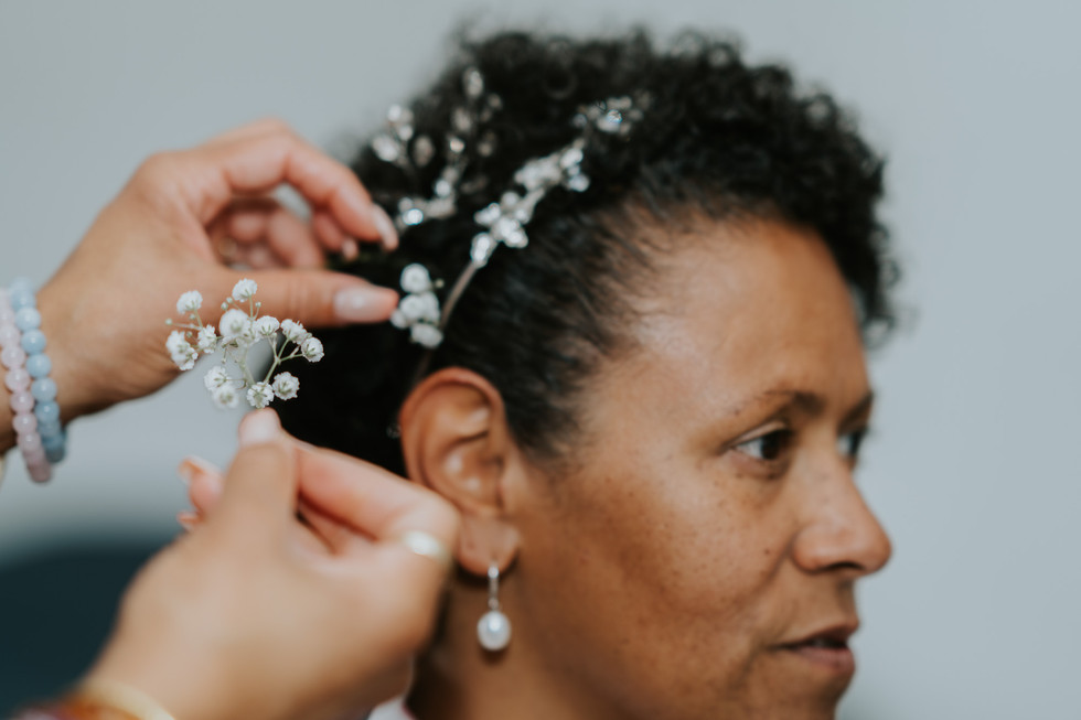 Woman having her curly hair styled with baby's breath accessory for wedding.