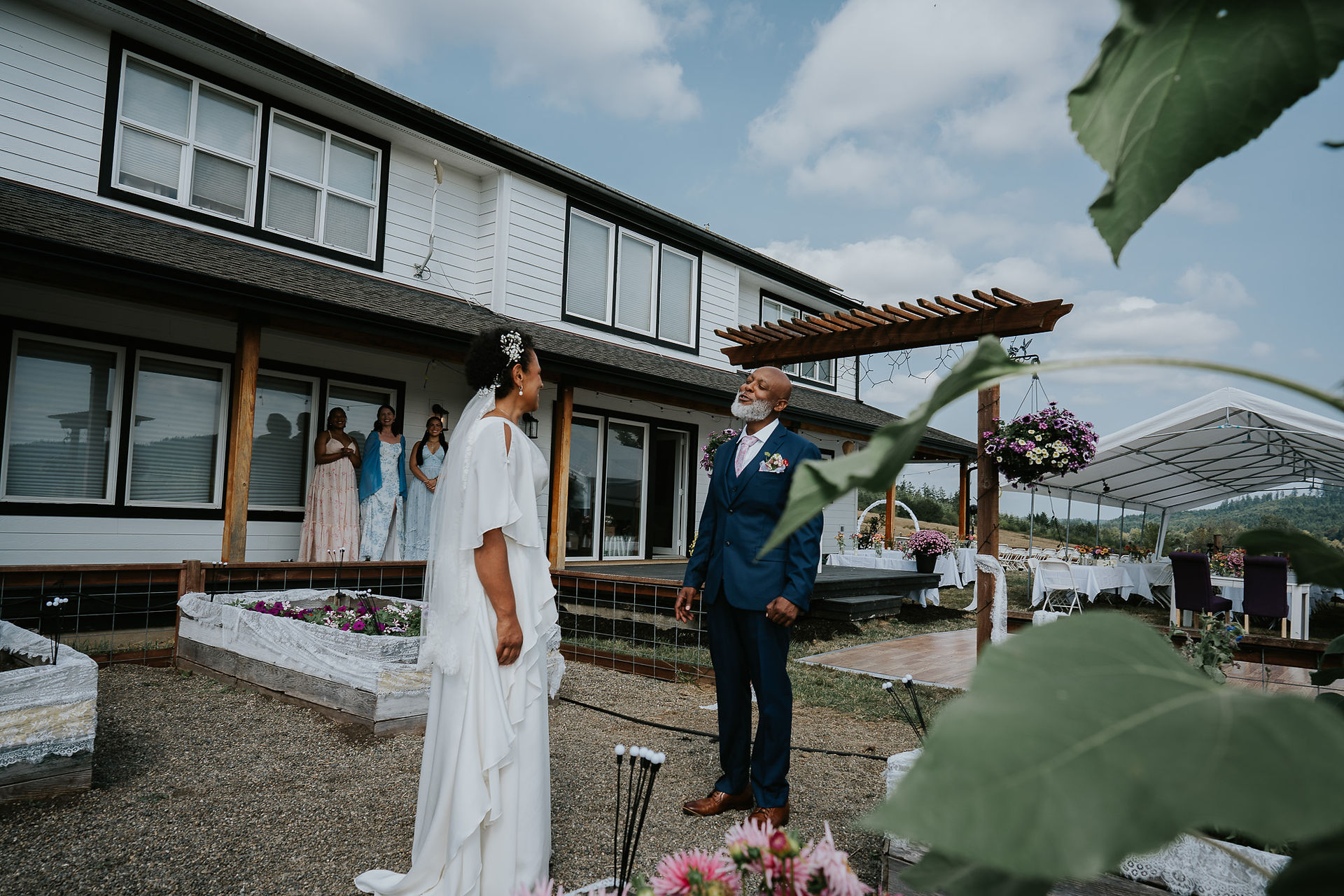 Bride in white dress facing man in blue suit at outdoor wedding.