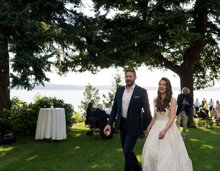 Bride and groom walking on grass at waterfront Wedding on Camano Island.