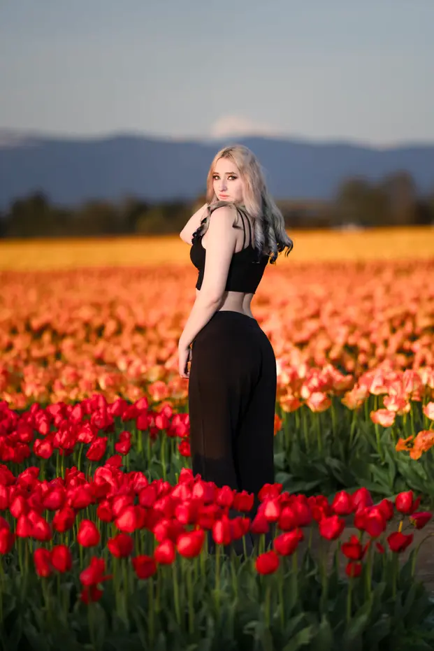 Young woman posing in vibrant red orange tulip field, Tulip Festival.