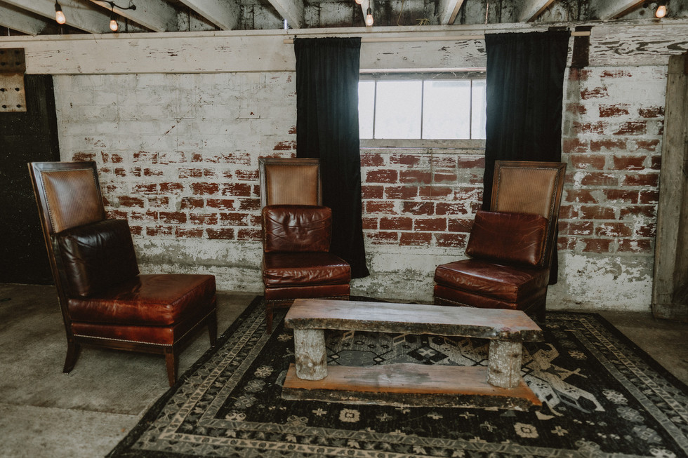 Inviting rustic lounge with leather chairs, coffee table, brick wall, rug.