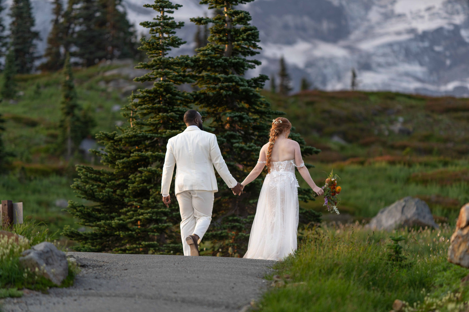 Bride and groom walking hand in hand through an alpine mountain trail during their elopement