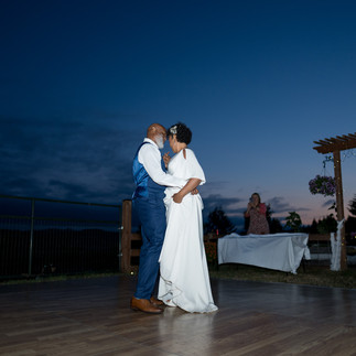 Couple dancing outdoors on a rustic dance floor at twilight. Intimate Farm Wedding.