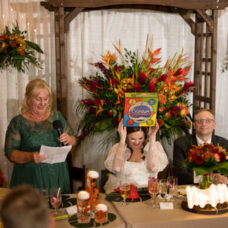 Woman holds "Cranium" box on head during wedding reception speech.