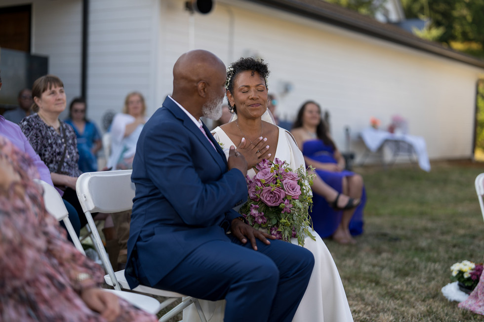 Emotional groom and bride touching chests during an intimate outdoor ceremony.