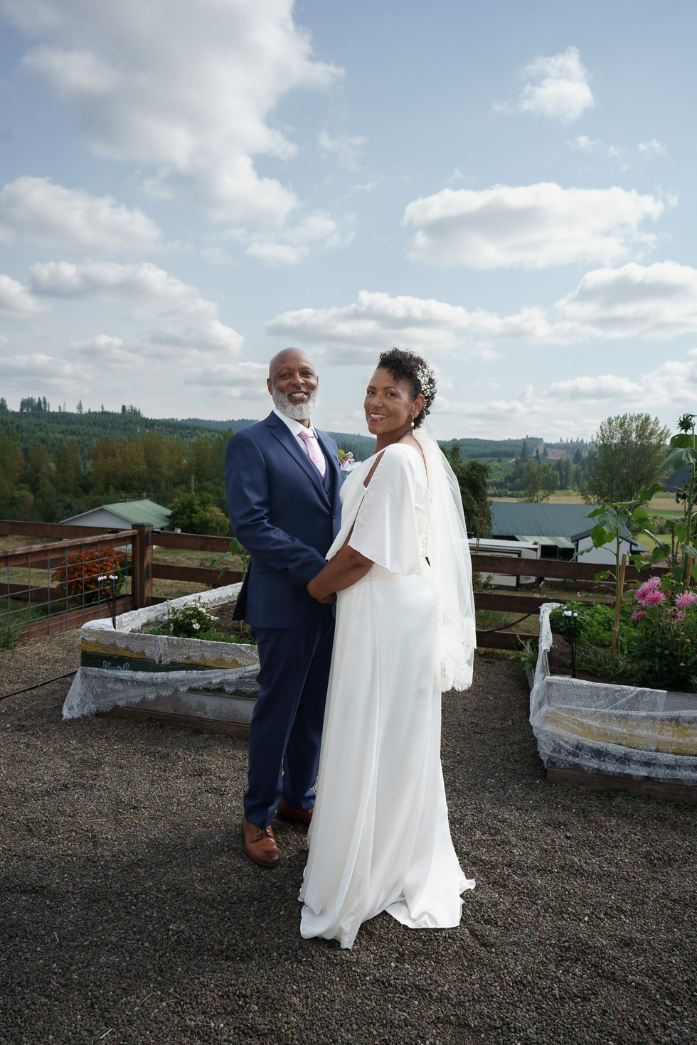 Smiling Black bride and groom holding hands at an outdoor farm wedding.
