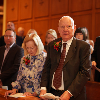 Older man and woman guests with boutonnieres at a formal wedding.