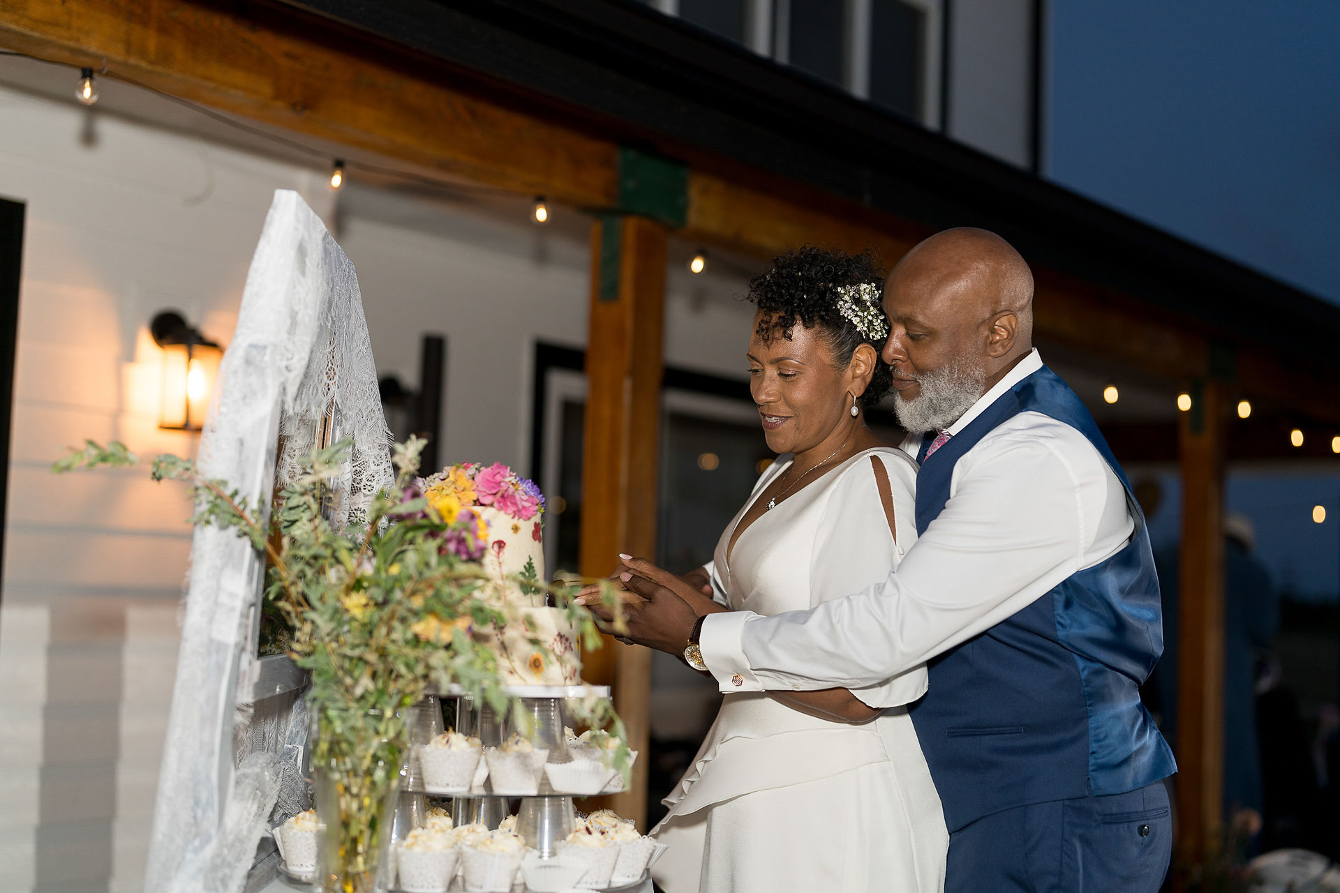 Black couple cutting their tiered wedding cake at reception.