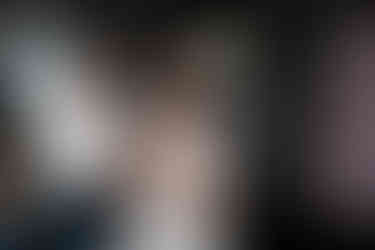 Man zipping up bride's elegant wedding dress, she poses confidently.