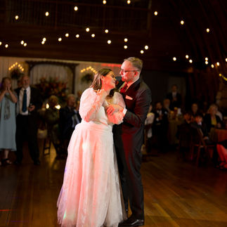 Happy couple dancing at wedding reception, romantic string lights overhead.