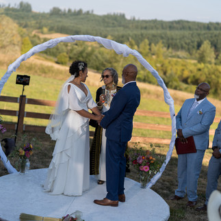 Bride and groom holding hands during intimate outdoor farm wedding ceremony.