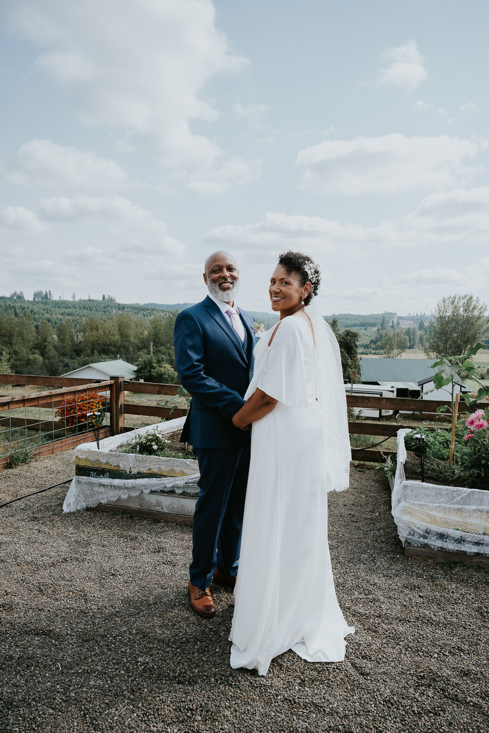 Smiling couple holding hands at their beautiful outdoor farm wedding.