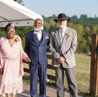 Three smiling older guests attending an outdoor farm wedding ceremony.