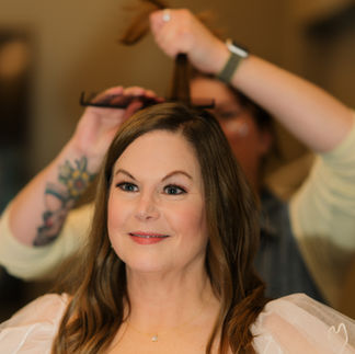 Smiling woman getting her hair styled by a professional hairdresser.