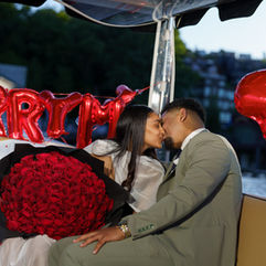 Couple kissing on boat, Marry Me balloons, red roses