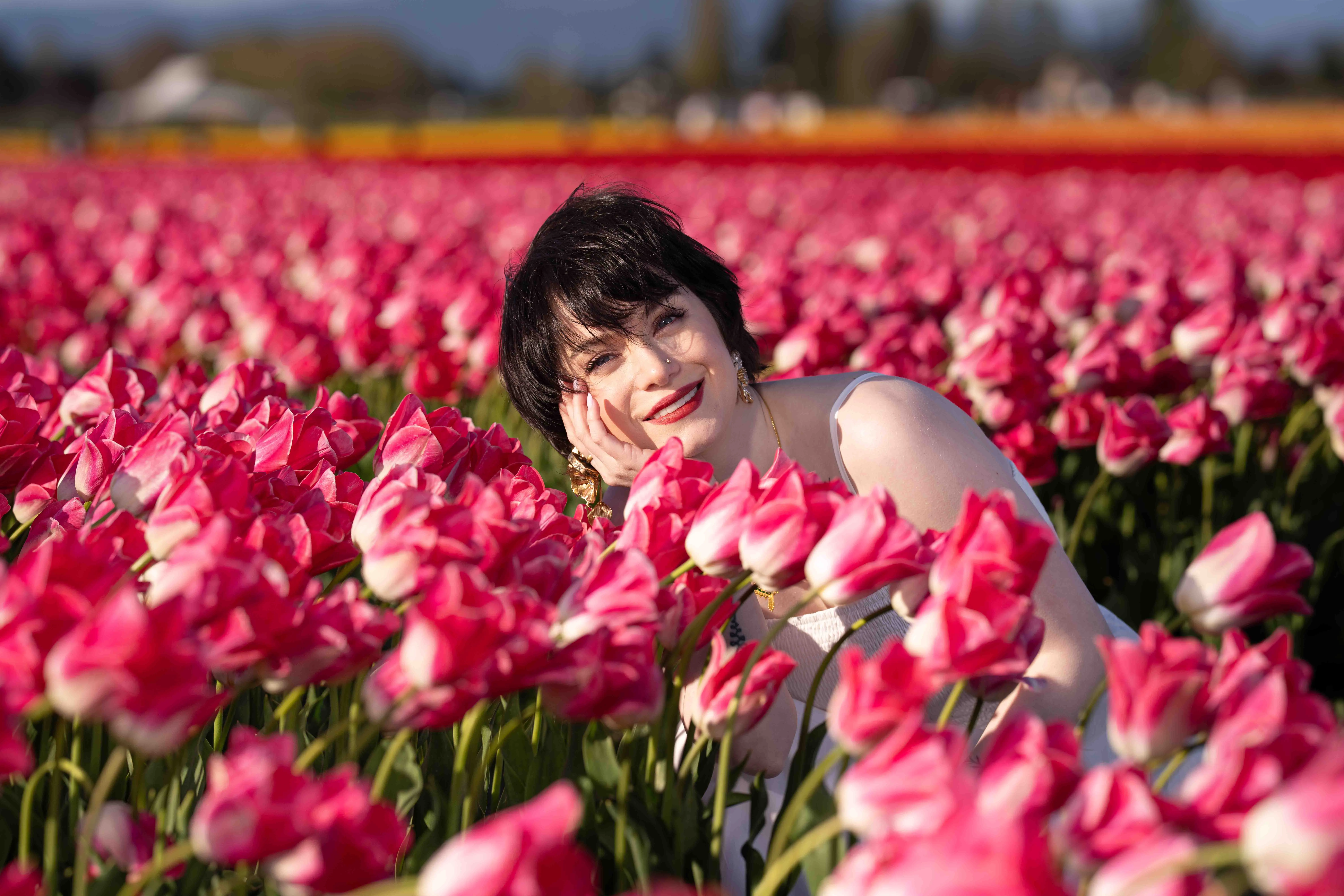 Smiling woman among vibrant pink tulips, enjoying the tulip festival 2026.