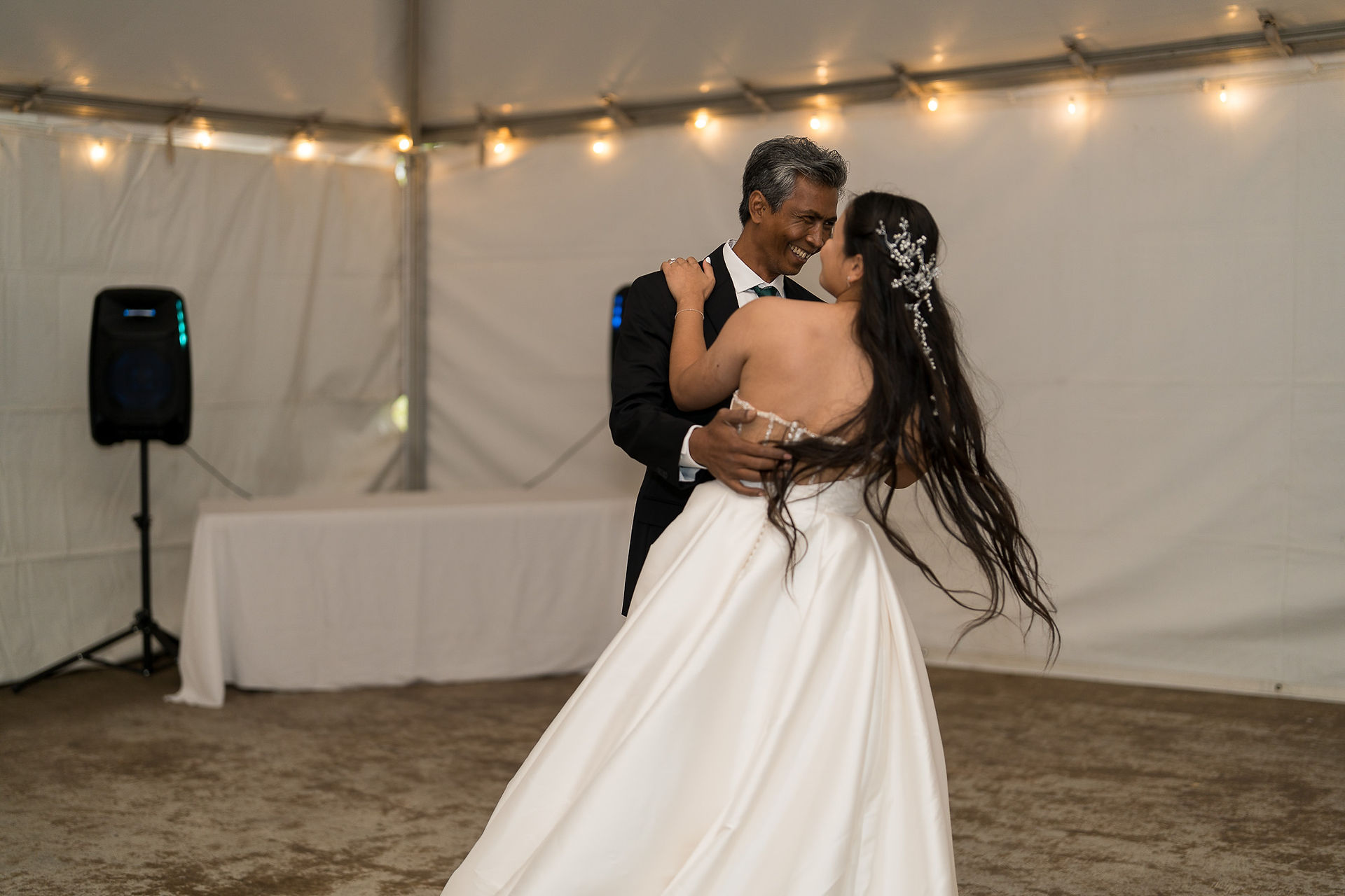 Couple dancing intimately at their wedding reception under tent lights.