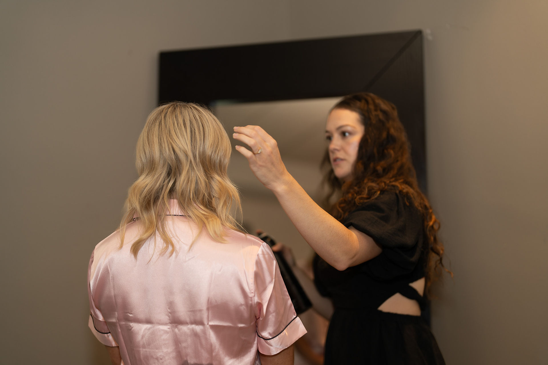 Bride getting her blonde hair styled for elegant summer wedding.