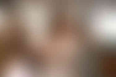 Bride in elegant wedding dress with arm tattoos smiling, getting ready.