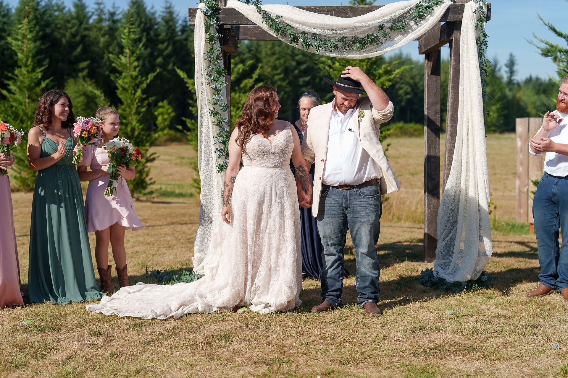 Bride and groom walking from decorated wedding arch outdoors.