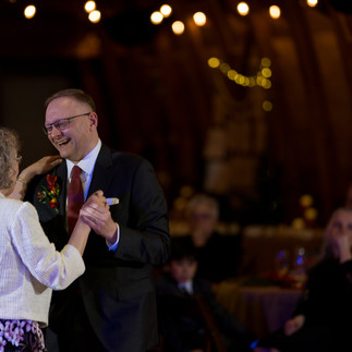 Man and woman dancing happily in festive reception hall with bokeh lights.