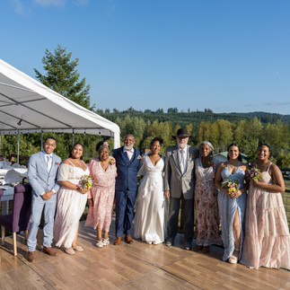 Diverse group of ten adults posing happily outdoors at a farm wedding.