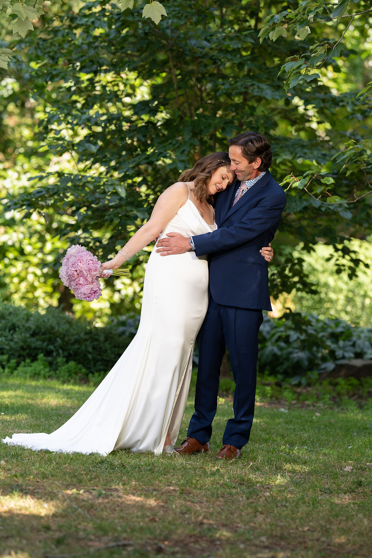 Bride and groom embracing affectionately with a lavender bouquet outdoors.