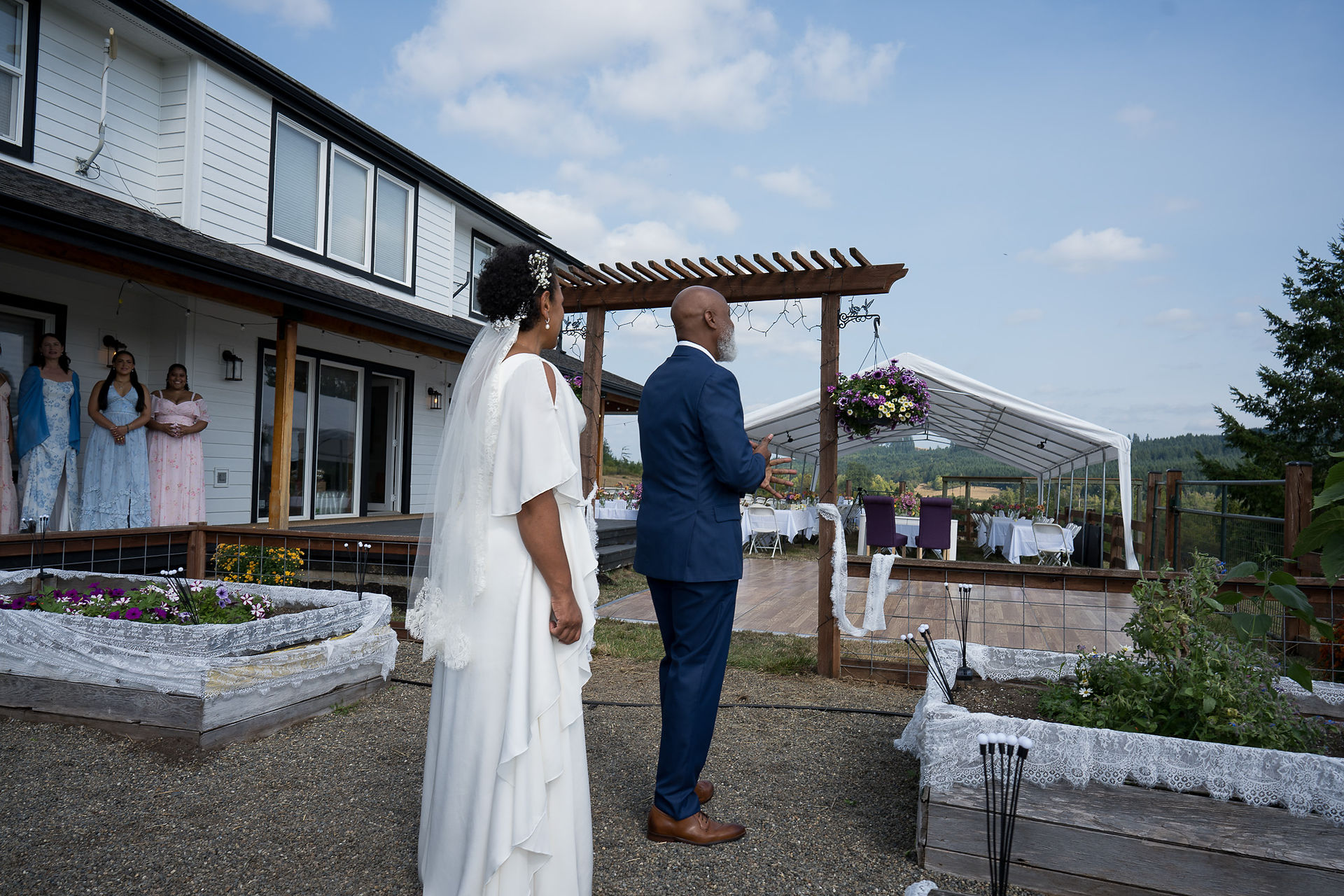 Bride and groom face intimate farm wedding reception tent outdoors.