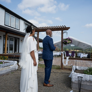 Bride and groom face intimate farm wedding reception tent outdoors.