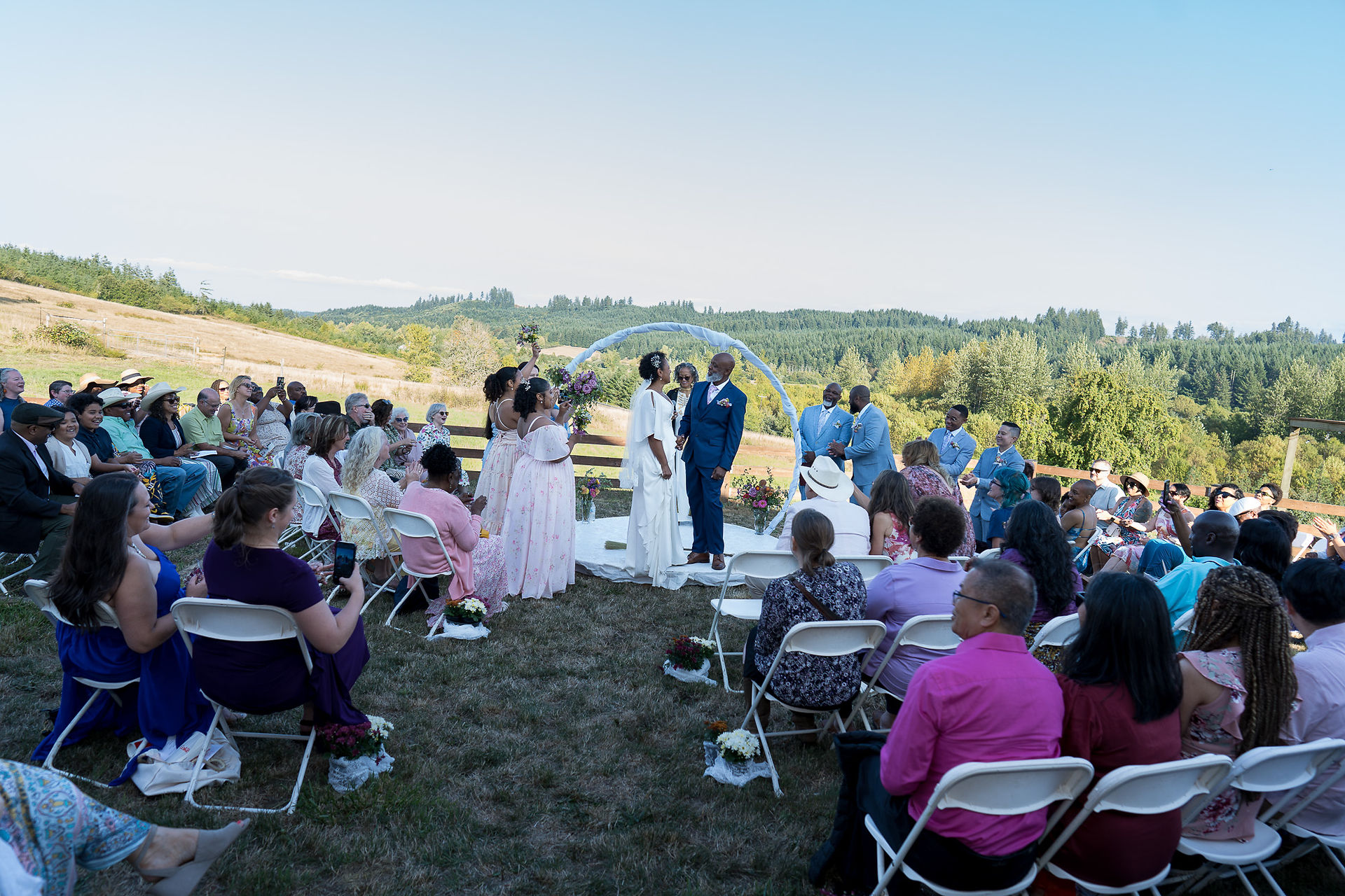 Wedding couple exchanging vows at intimate outdoor farm ceremony with guests.