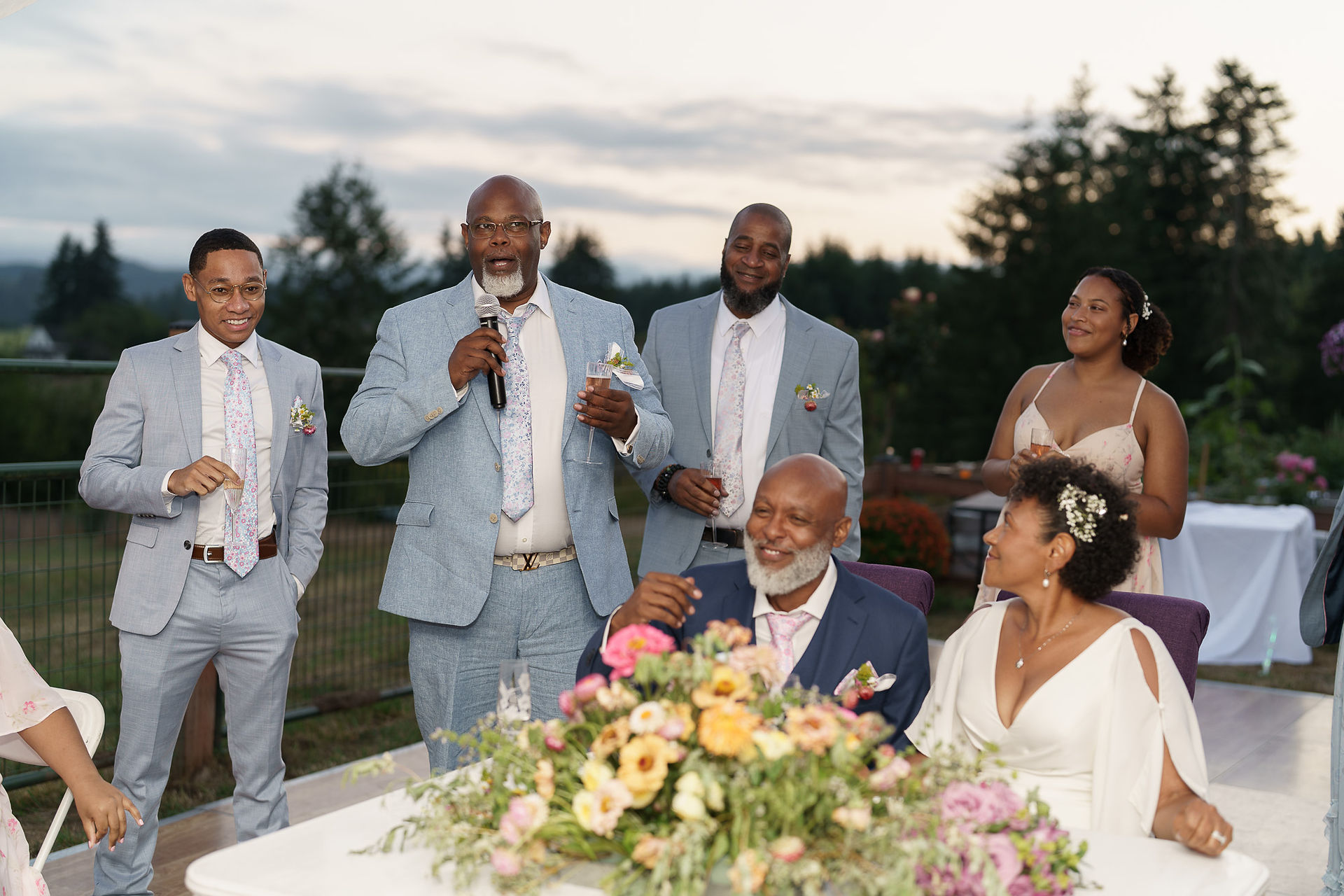 Older man gives speech at outdoor wedding reception for guests