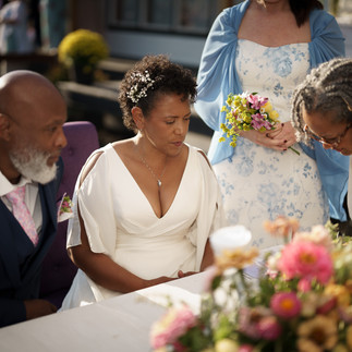 Mature Black couple in wedding attire share intimate moment outdoors.