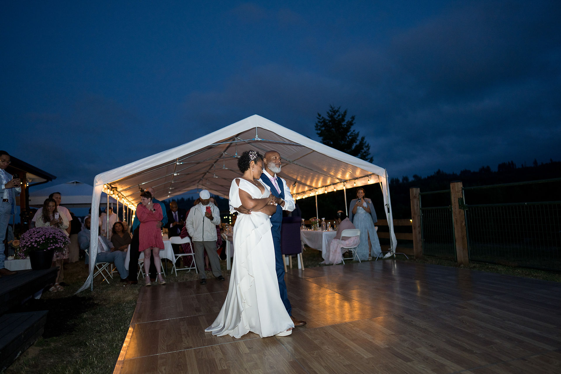 Couple dances under illuminated tent at an intimate farm wedding.