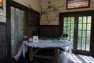 Rustic guest table with "GUEST TABLE" sign, decorated with branches.