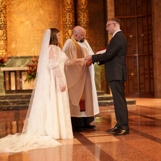 Bride and groom hold hands with priest at Bastyr Chapel, Kenmore WA.