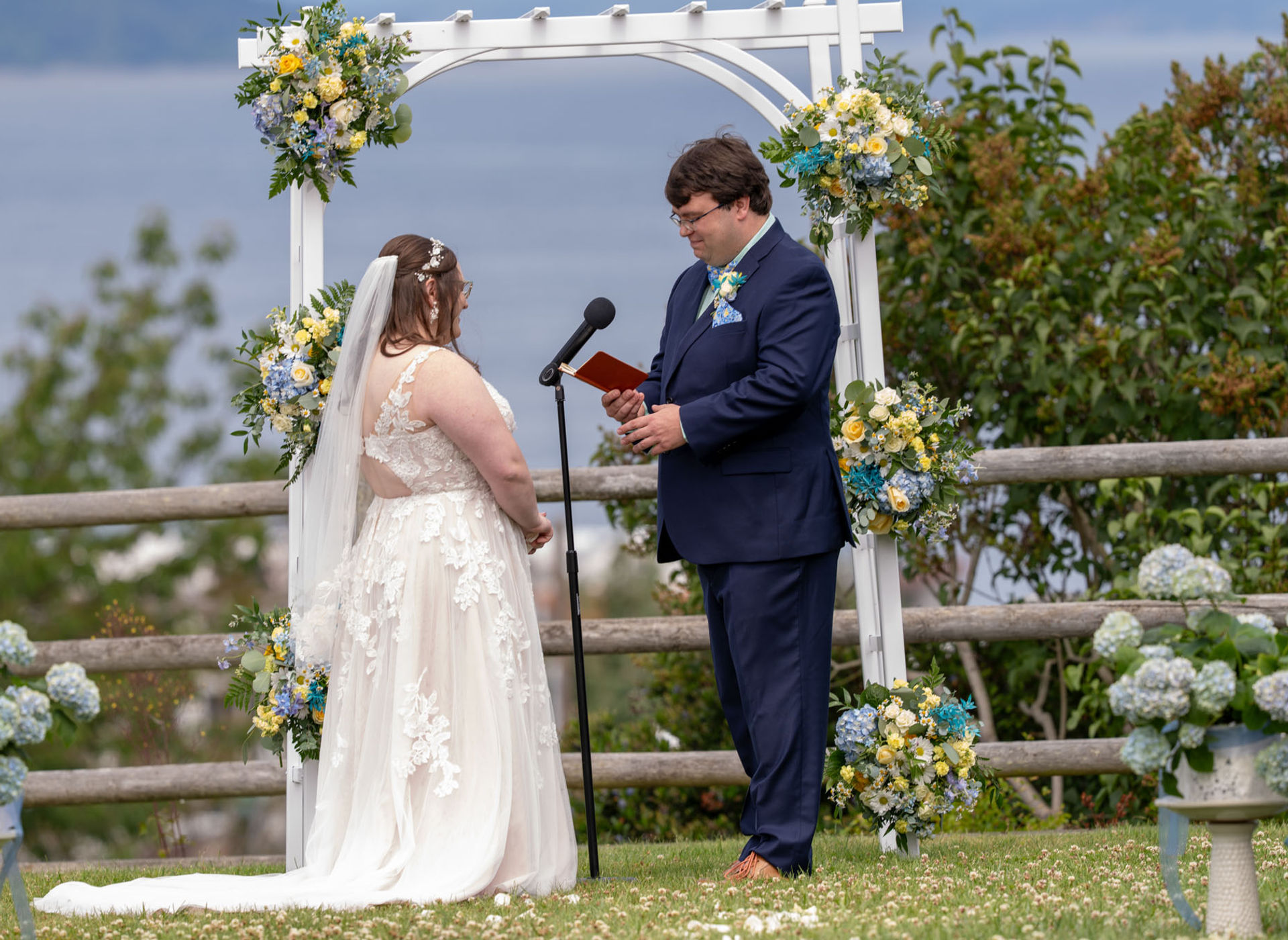 Bride and groom exchanging vows at outdoor wedding ceremony with floral decor.